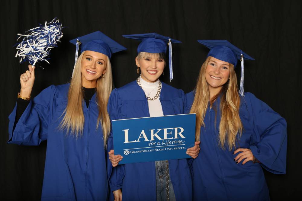 three friends with pom pom and Laker for a Lifetime sign